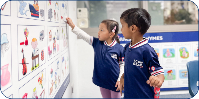 Two students in an I Can Read class pointing to a picture board Two students in an I Can Read class pointing to a picture board
